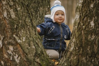 Middle Eastern baby boy climbing tree