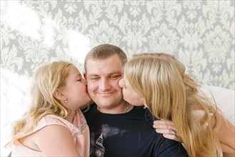 Middle Eastern daughters kissing father on cheek