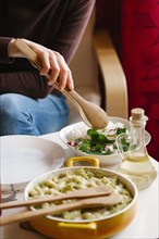 Woman serving salad with wooden tongs