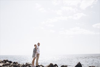 Middle Eastern couple standing on rocks near ocean