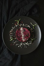 Sesame seeds and garnish on red food on plate