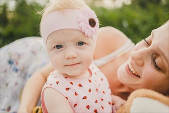 Mother posing with baby daughter wearing headband