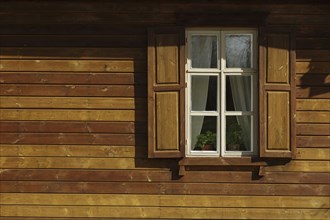 Window with shutters on wooden wall