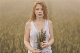 Middle Eastern teenage girl holding wheat in field