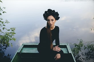 Middle Eastern woman wearing black dress in boat on lake