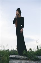 Middle Eastern woman wearing black dress standing on stone