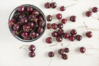 Cherries and bowl on white wooden table