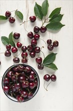 Cherries and bowl on white wooden table
