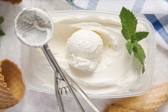 Scoop of ice cream in container with mint near cones
