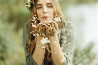Middle Eastern woman blowing dandelion seeds