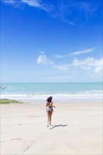 Hispanic woman running on beach