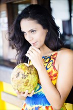 Hispanic woman drinking fresh coconut milk