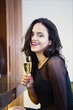 Hispanic woman drinking glass of champagne