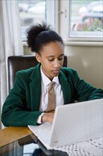 Black girl wearing school uniform using laptop