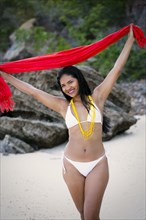 Smiling Mixed Race woman wearing bikini holding red scarf