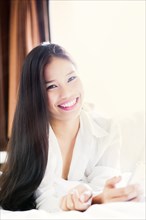 Portrait of smiling Asian teenage girl laying on bed
