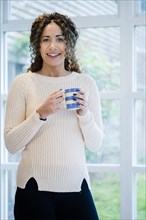 Woman standing near window holding coffee cup