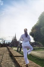 Asian woman practicing yoga near temple