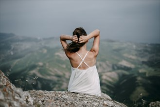 Caucasian woman sitting on rock overlooking landscape