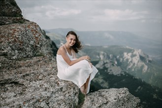 Smiling Caucasian woman sitting on rock overlooking landscape