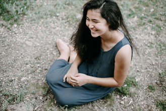 Smiling Asian woman sitting on ground
