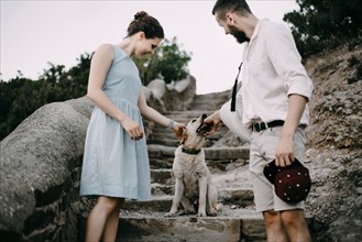 Caucasian couple playing with dog on stone staircase