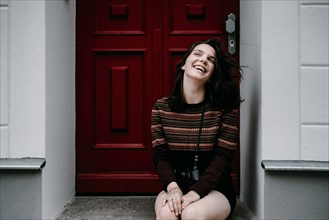 Laughing Caucasian woman sitting in doorway