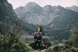 Caucasian woman sitting on bench in mountains
