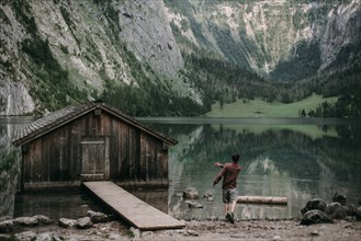 Caucasian man skipping stones in mountain lake