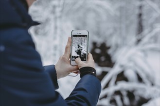 Caucasian woman photographing snow with cell phone