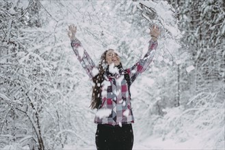 Snow falling on Caucasian woman in forest