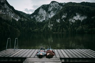 Caucasian couple laying on dock near scenic view of mountain