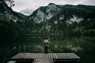 Caucasian man standing on dock admiring scenic view of mountain