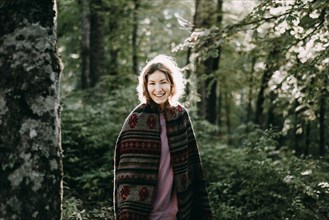 Smiling Caucasian woman wearing shawl in forest