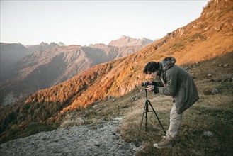 Caucasian man photographing valley from mountain