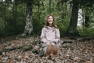 Caucasian woman sitting in autumn leaves in forest