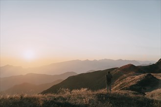 Caucasian man admiring scenic view of sunset on mountain