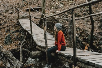 Caucasian woman sitting on footbridge in woods