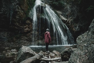 Caucasian woman standing on rock admiring waterfall