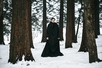Caucasian man with beard wearing robe in forest during winter