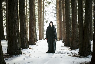 Caucasian man with beard wearing robe in forest during winter