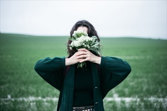 Caucasian woman holding wildflowers in front of face