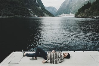 Caucasian man laying on dock at waterfront