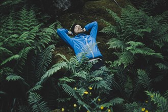 Caucasian man laying on rock in foliage