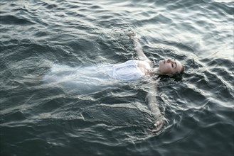 Caucasian woman wearing a dress floating in water