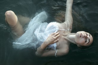 Caucasian woman wearing a dress floating in water