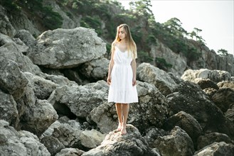 Caucasian woman wearing dress standing on rocks
