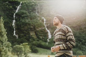 Pensive Caucasian man wearing sweater and hat outdoors