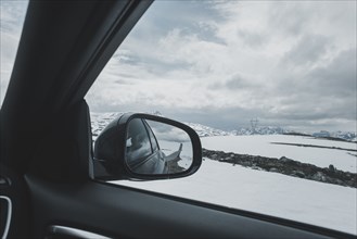 Car side-view mirror near winter landscape