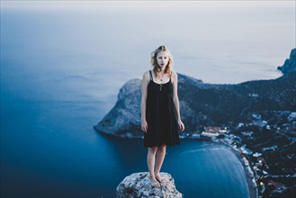 Caucasian woman standing on rock near ocean